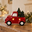 Red ceramic LED Christmas tree truck glowing on an aged oak mantel in a cream country home