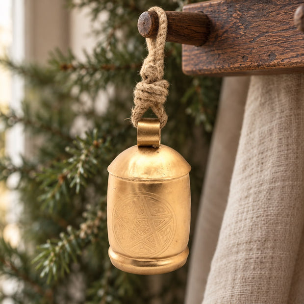 Large Brass Gold Cow Bell On Rope, gold-coloured bell hanging by rope from a wooden peg