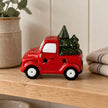 Red ceramic Christmas tree truck with star cut-outs on a pale oak kitchen shelf