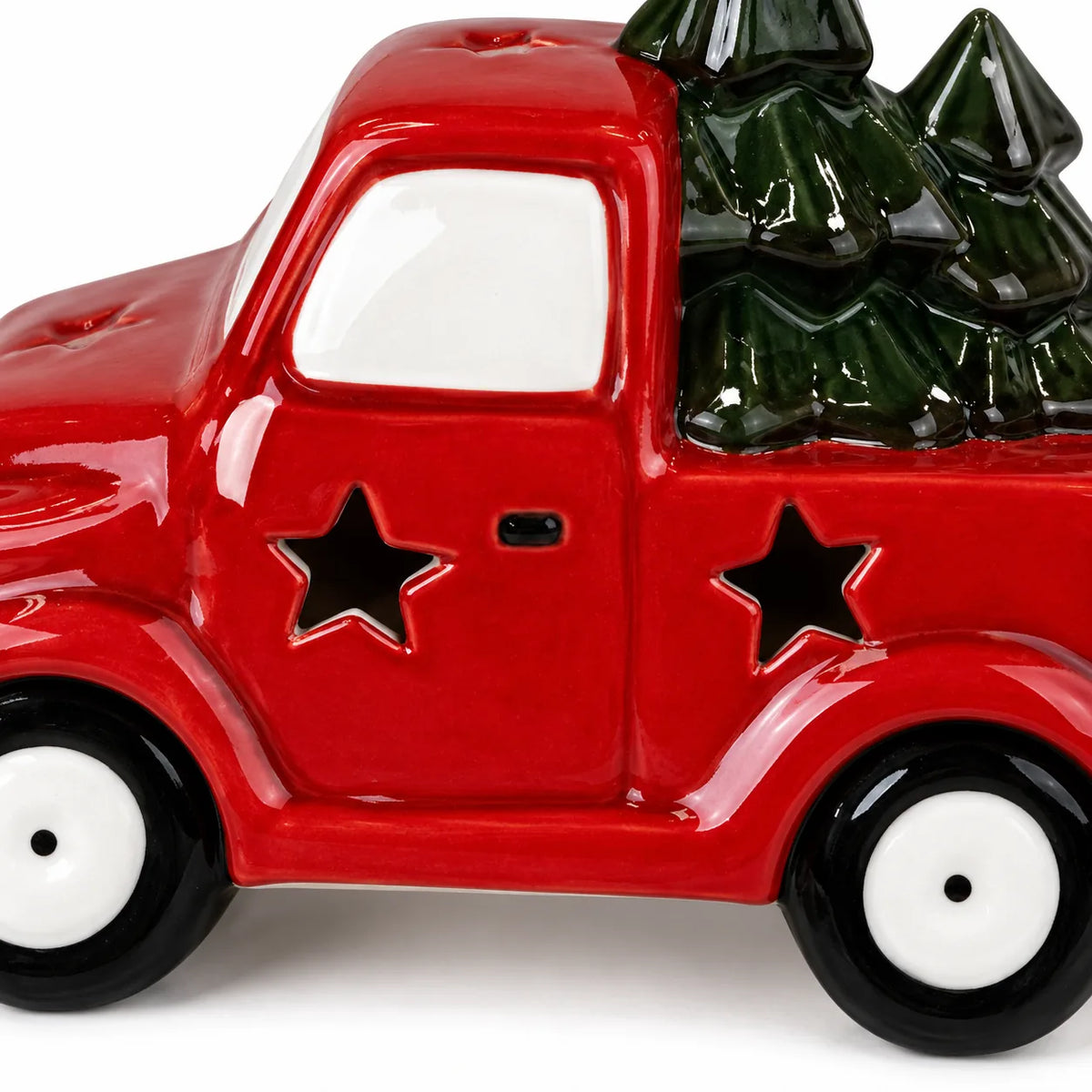 Close-up of the red ceramic truck's star cut-outs, white wheels and dark green trees