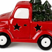 Close-up of the red ceramic truck's star cut-outs, white wheels and dark green trees