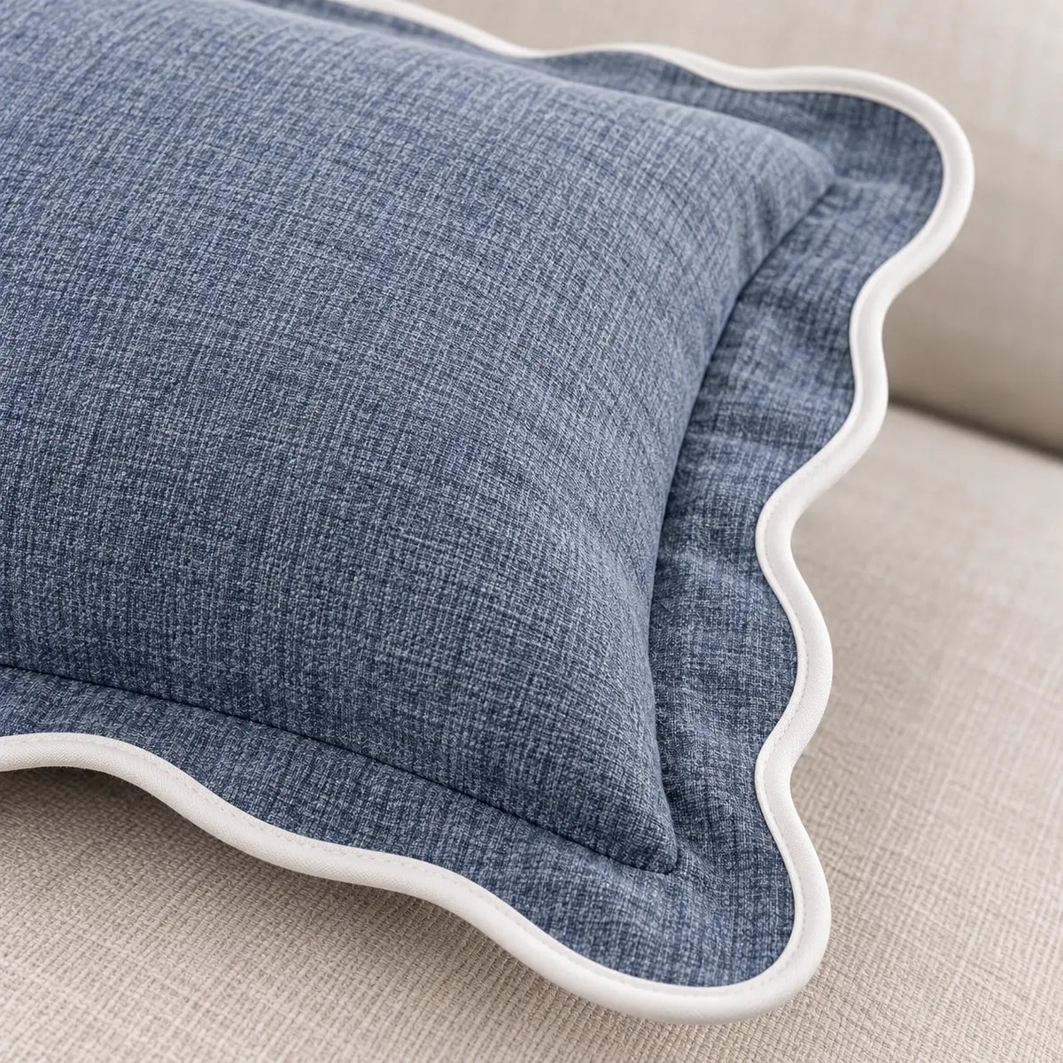 Close-up of a light blue and white scalloped cushion cover by Starlight Express, showcasing soft furnishings with decorative stitching.
