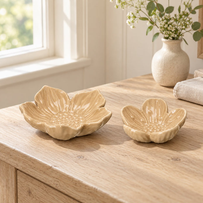 Two beige flower dishes on a wooden chest