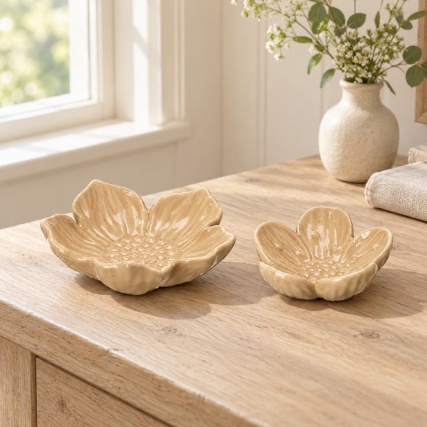 Two beige flower dishes on a wooden chest