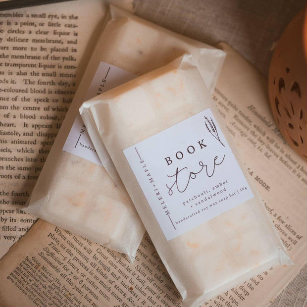 Cream wax melt snap bar labelled Book Worm in clear packaging on open books