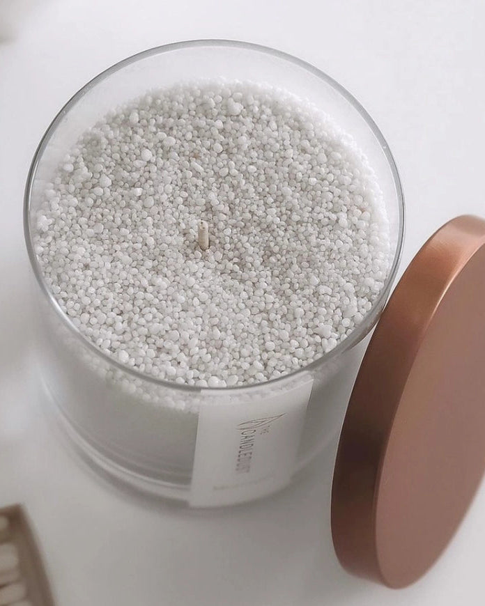 White scented candle in a sand jar with dark honey fragrance, part of The Candledust home fragrance collection.