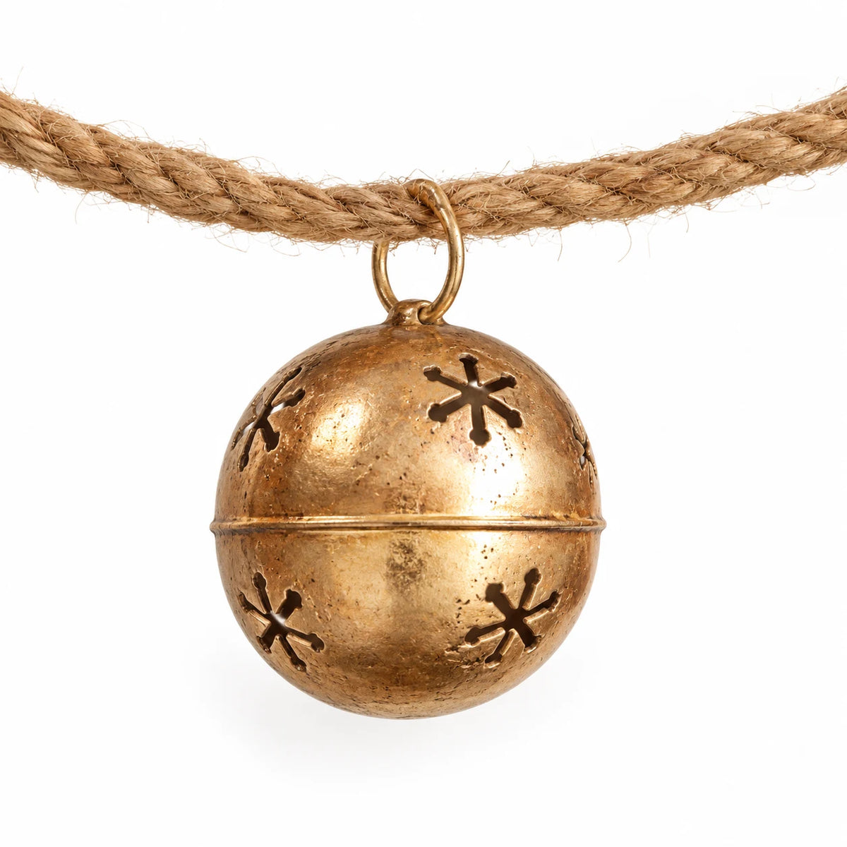 Close-up of a gold sleigh bell showing snowflake cut-outs and its cord attachment.