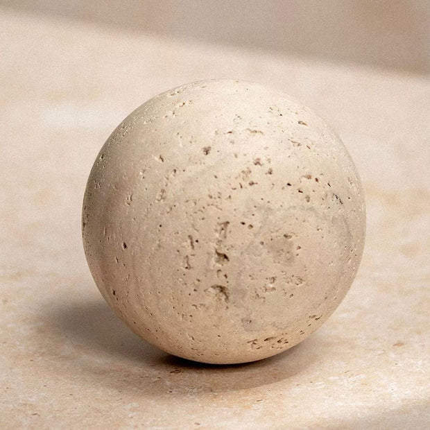 Travertine Round Ball Stone Ornament, pale travertine sphere on a stone surface