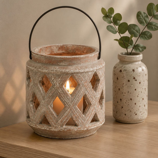 Siena Matt Brown Stone Lattice Hurricane Lantern, stone lattice lantern with a dark handle beside a ceramic vase