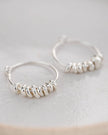 Silver hoop earrings with bead detailing on a light background