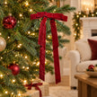 One burgundy long-tail velvet bow styled on an illuminated Christmas tree.