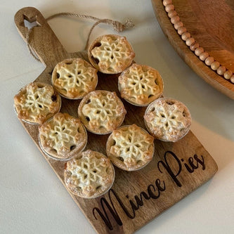 Wooden board with mini pies and 'Mince Pies' inscription on a white surface