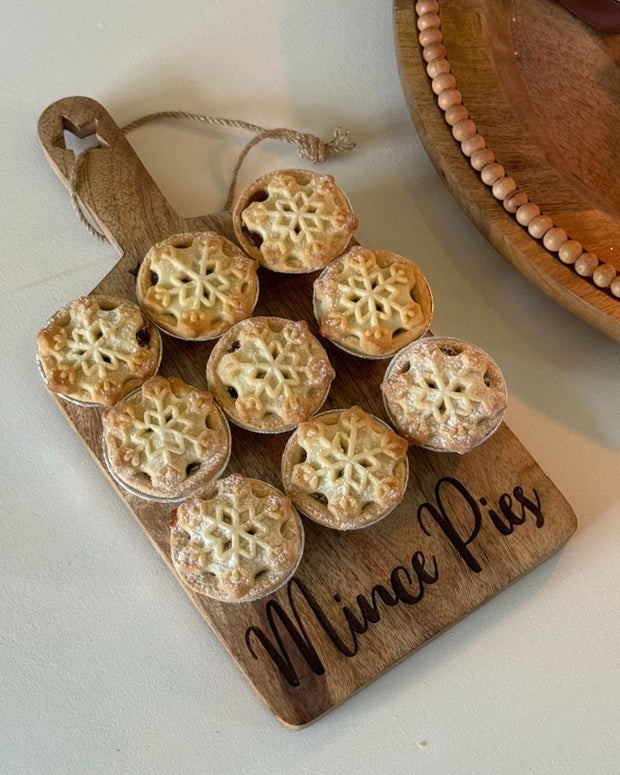 Wooden board with mini pies and 'Mince Pies' inscription on a white surface