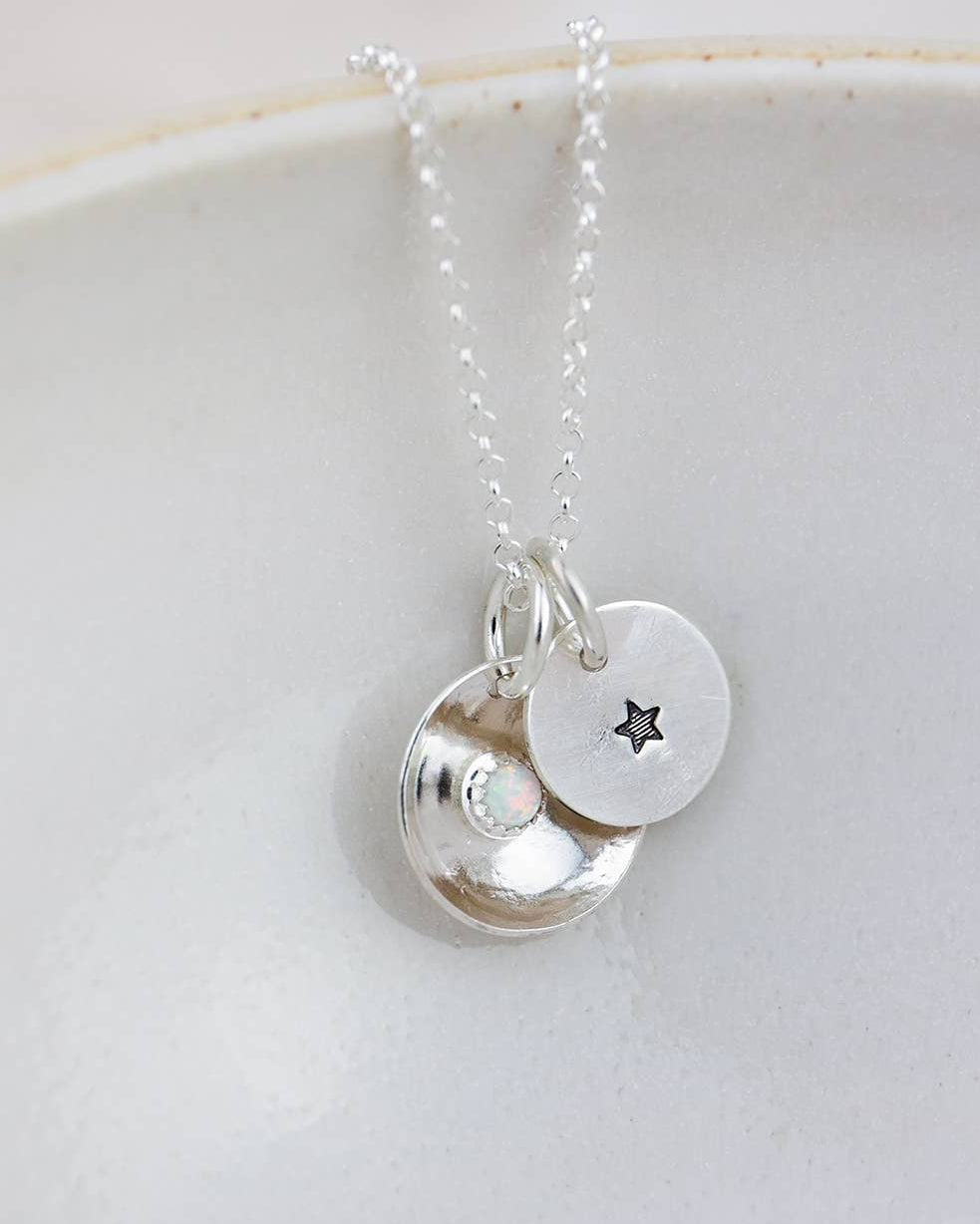 Silver necklace with two round pendants on a white dish