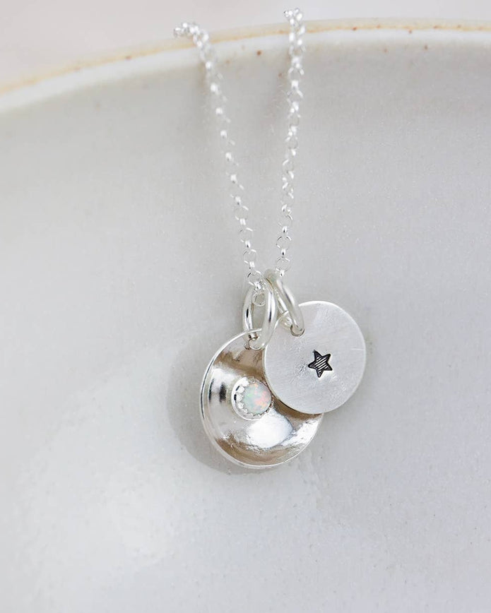 Silver necklace with two round pendants on a white dish