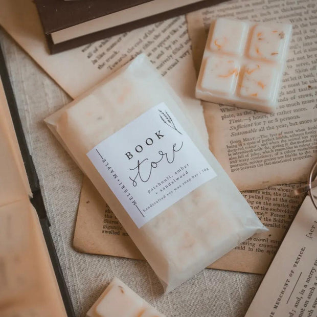 Cream wax melt snap bar labelled Book Worm beside a loose wax piece on book pages