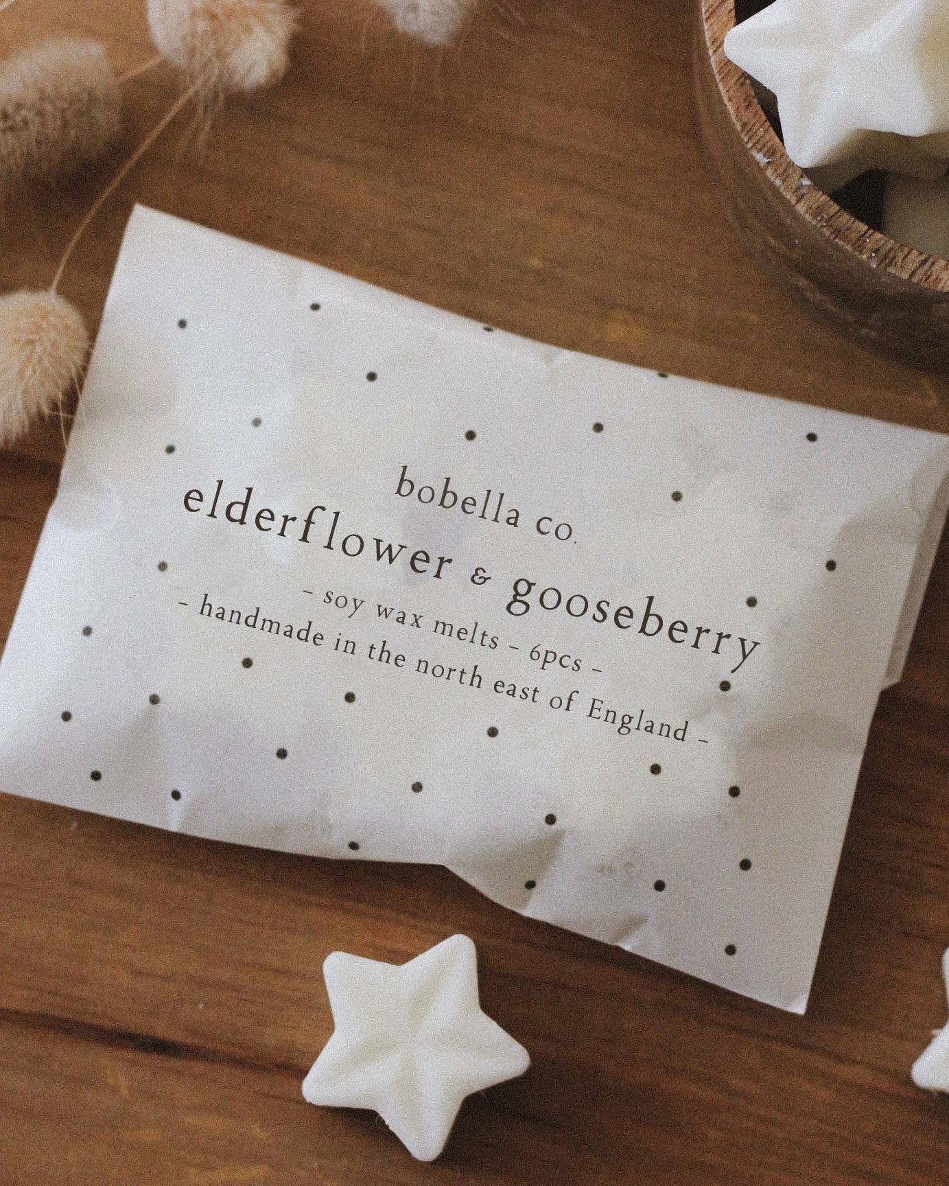 Wax melts packaging with star-shaped wax melts on a wooden surface