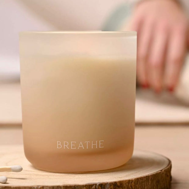 Serenity Breathe Candle 270g Eucalyptus Sage & Vetiver, cream candle in a peach-toned jar on a wooden coaster