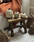 Decorative pumpkins on a small wooden stool with a cozy blanket and rustic decor in the background.