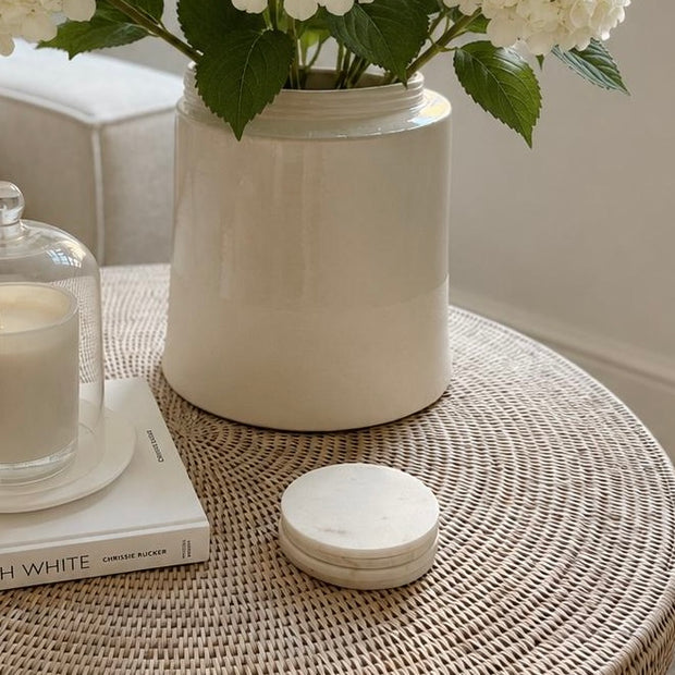 Round Marble Coasters - Set of Four, stack of round pale marble coasters beside a vase