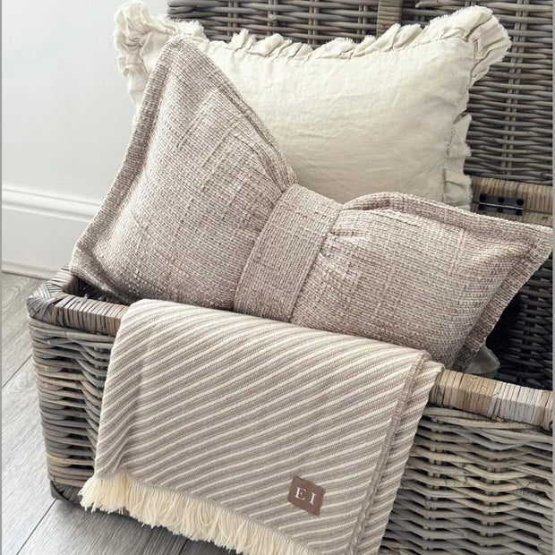 Beige Velveteen Bow Cushion, beige bow-shaped cushion displayed in an open woven trunk