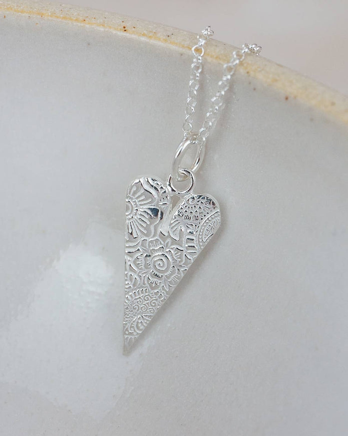 Silver heart-shaped pendant on a chain against a light background