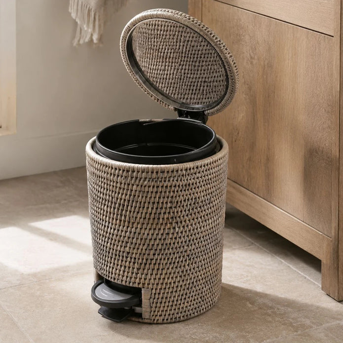 Wickham Rattan Round Pedal Waste Paper Bin, woven pedal bin with its lid open beside a bathroom cabinet