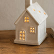 Neutral Ceramic Light Up LED House, glowing cream ceramic house on a wooden table
