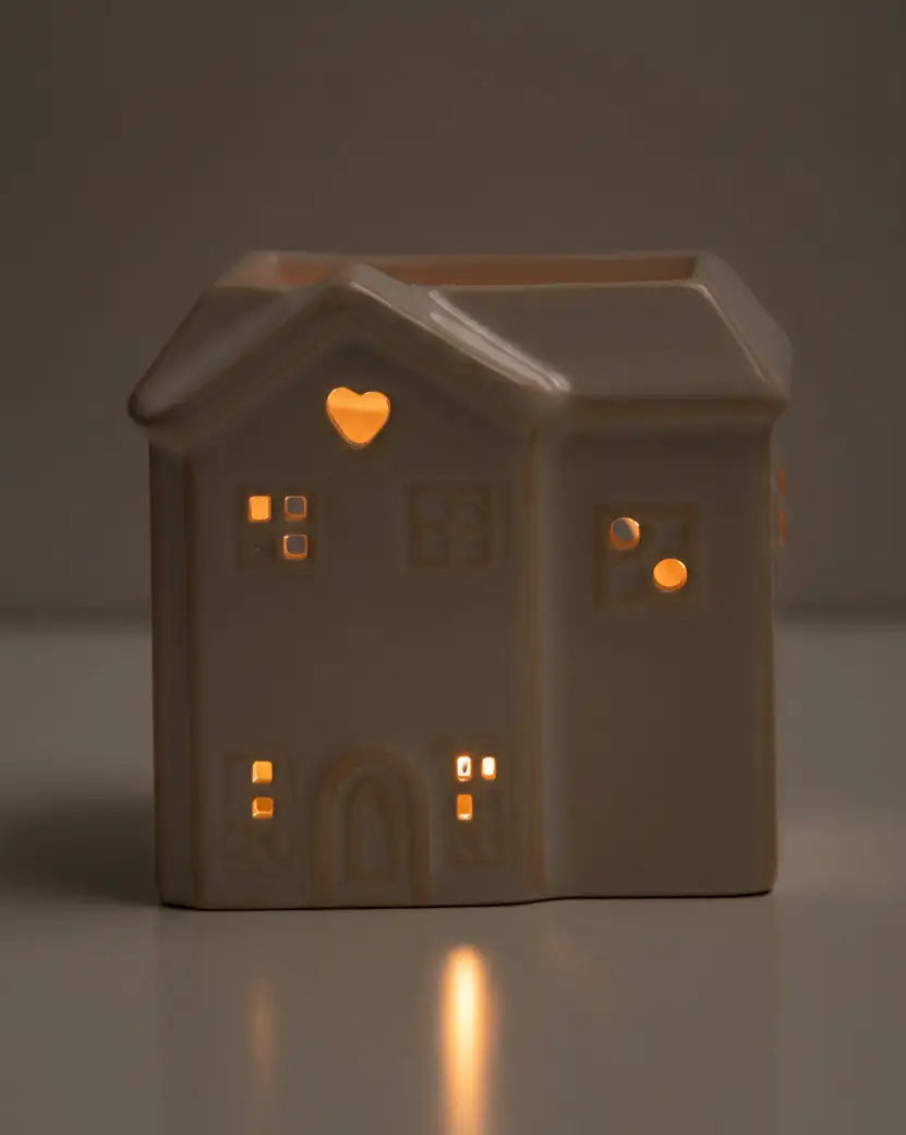 House-shaped ceramic lantern with glowing windows on a dark background