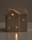 House-shaped ceramic lantern with glowing windows on a dark background