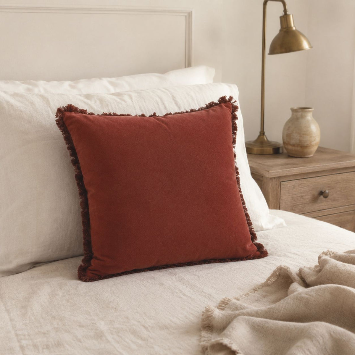 Burgundy Frayed Edge Cushion Cover, burgundy cushion against pillows on a cream bed