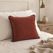 Burgundy Frayed Edge Cushion Cover, burgundy cushion against pillows on a cream bed