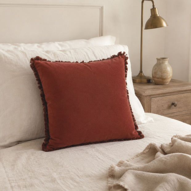 Burgundy Frayed Edge Cushion Cover, burgundy cushion against pillows on a cream bed