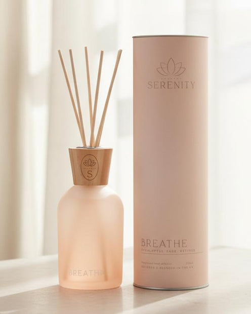 Serenity Breathe Reed Diffuser 220ml Eucalyptus Sage & Vetiver, peach diffuser bottle with reeds beside a pink tube by a window