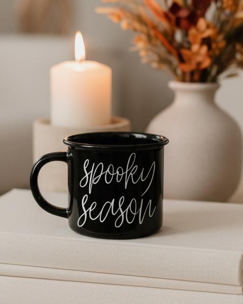 Black Ceramic Spooky Season Autumn Coffee Mug, black Spooky Season mug beside a candle and autumn vase