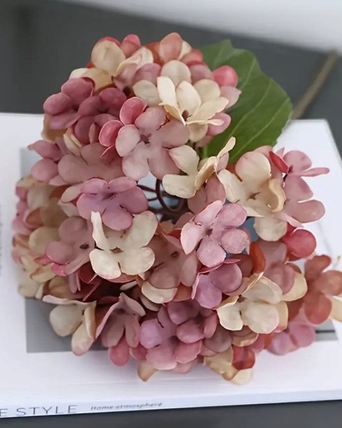 Artificial pink hydrangea stem from Starlight Express, featuring short, vibrant pink blossoms and realistic green foliage.