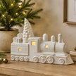 White Ceramic Light-Up LED Train, white ceramic train with glowing windows beside a Christmas tree