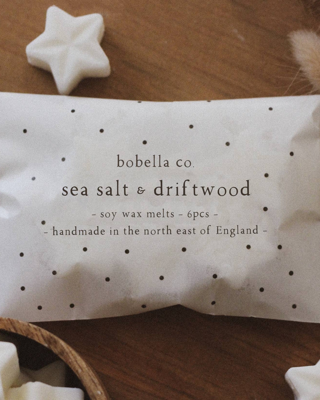 Sea salt and driftwood wax melts packaging with star-shaped melts on a wooden surface.