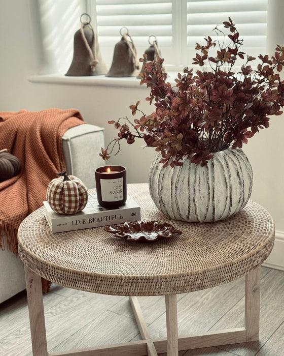 Round woven coffee table with decorative items in a cozy living room.