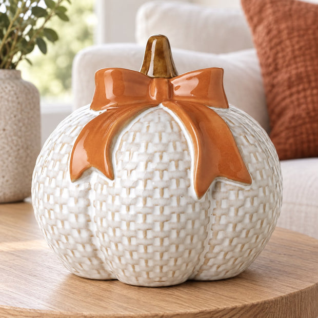 White Ceramic Pumpkin With Orange Bow, white textured ceramic pumpkin with an orange bow on a side table