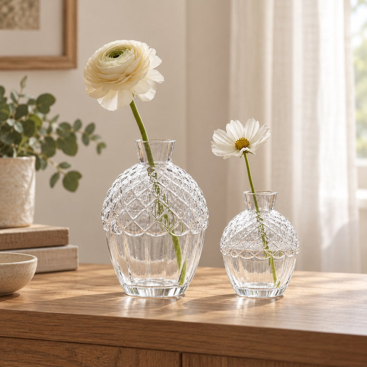 Two glass acorn vases with white flowers