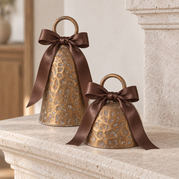 Brass Metal Cloche Cow Bell, two brass cloche bells decorated with brown bows on a mantel