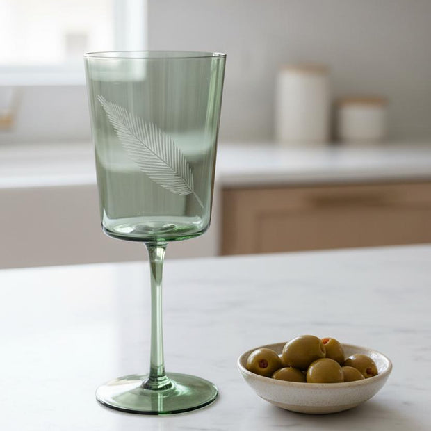 Green Palm Wine Glass, green stemmed wine glass beside a bowl of olives