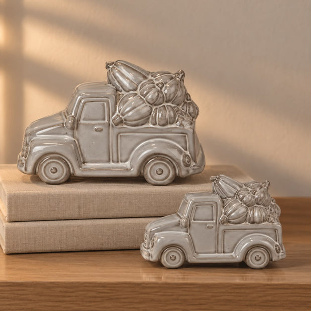 Glazed Neutral Ceramic Truck With Pumpkins, two glazed ceramic pumpkin trucks on stacked books