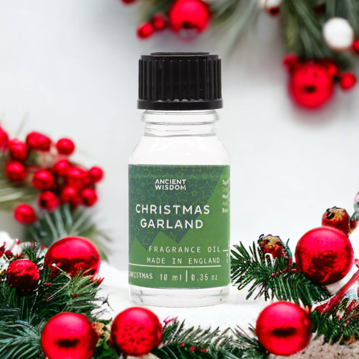 Ancient Wisdom Christmas Garland Fragrance Oil 10ml with festive holiday scent in a clear glass bottle with a black cap.