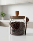 Glass coffee storage jar with dark wood lid and spoon, ideal for kitchen and dining organization by Starlight Express.