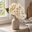 Artificial Short Soft Cream Hydrangea Stem, cream hydrangea stems in a taupe vase beside a window