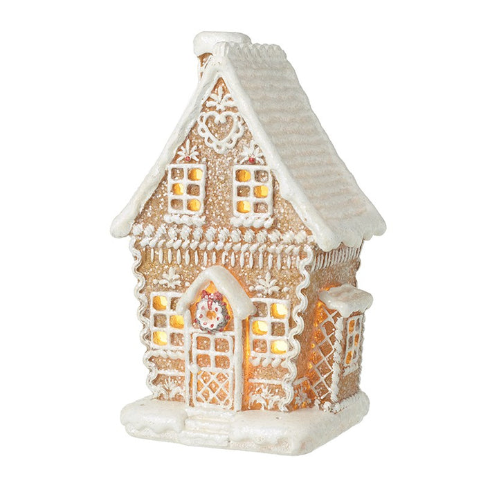 Decorated gingerbread house with white icing detail and glowing windows on a white background