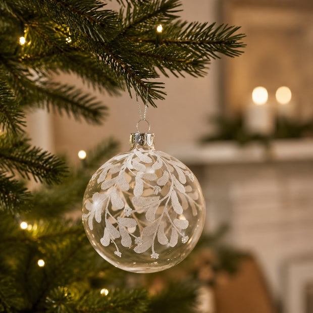 Clear Glass Bauble With White Leaves, clear bauble with white leaves hanging on a tree