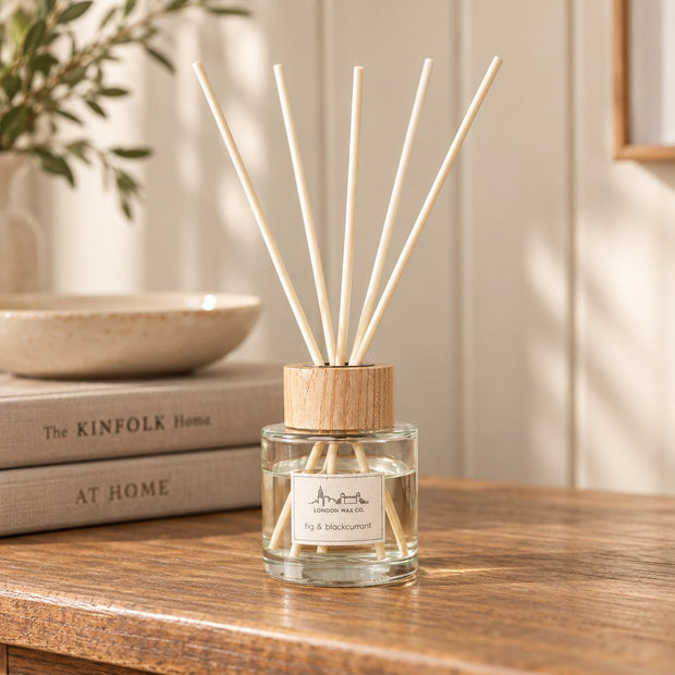 London Wax Company Reed Diffuser - Fig and Blackcurrant, clear reed diffuser with wooden collar beside books